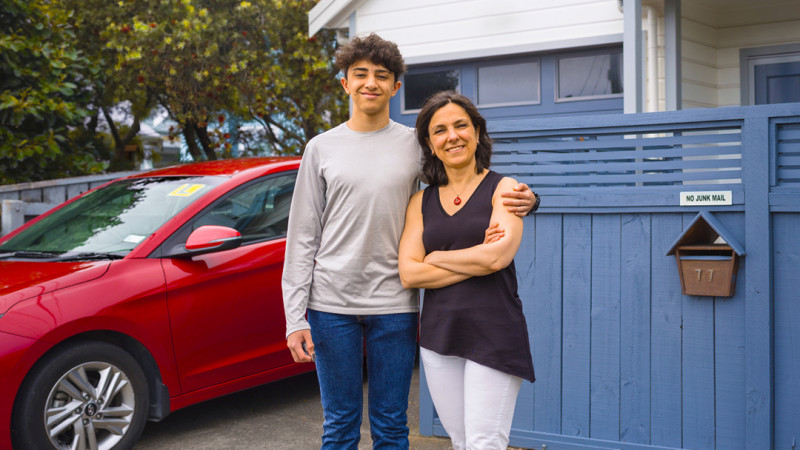 Ilgaz and Hülya standing next to a red car